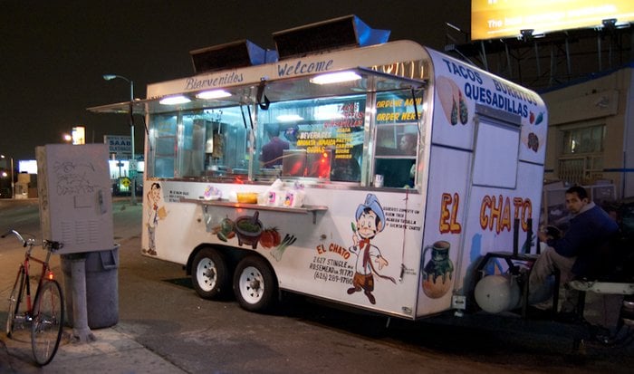 The El Chato taco truck parked at night with its lights on