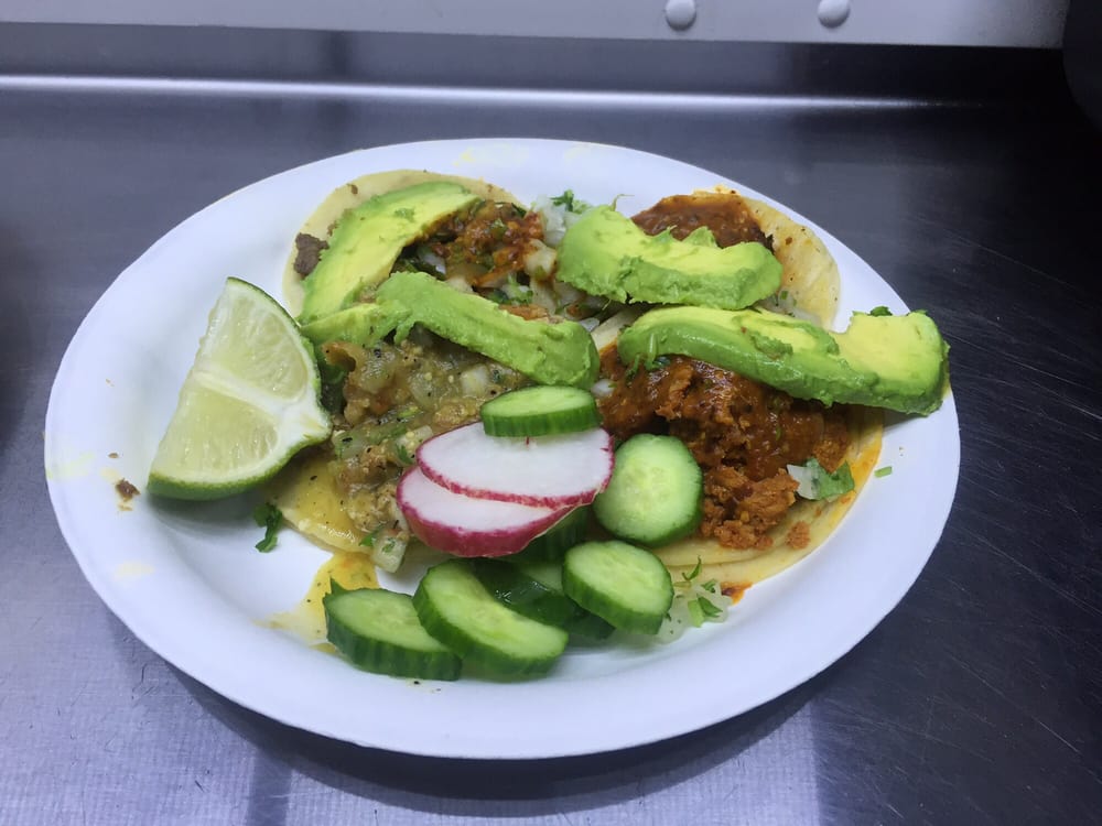 Tacos with avocado slices, radish, cucumber and lime